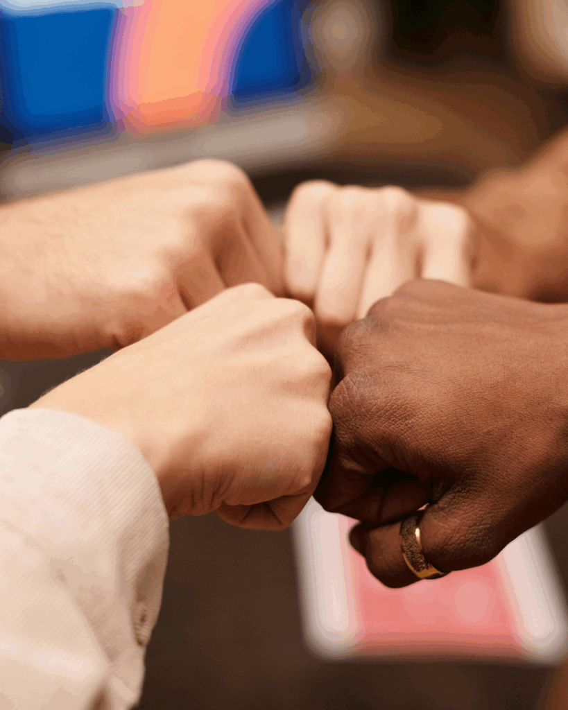 Mixed coloured hands doing fist bump - illustrating teamwork
