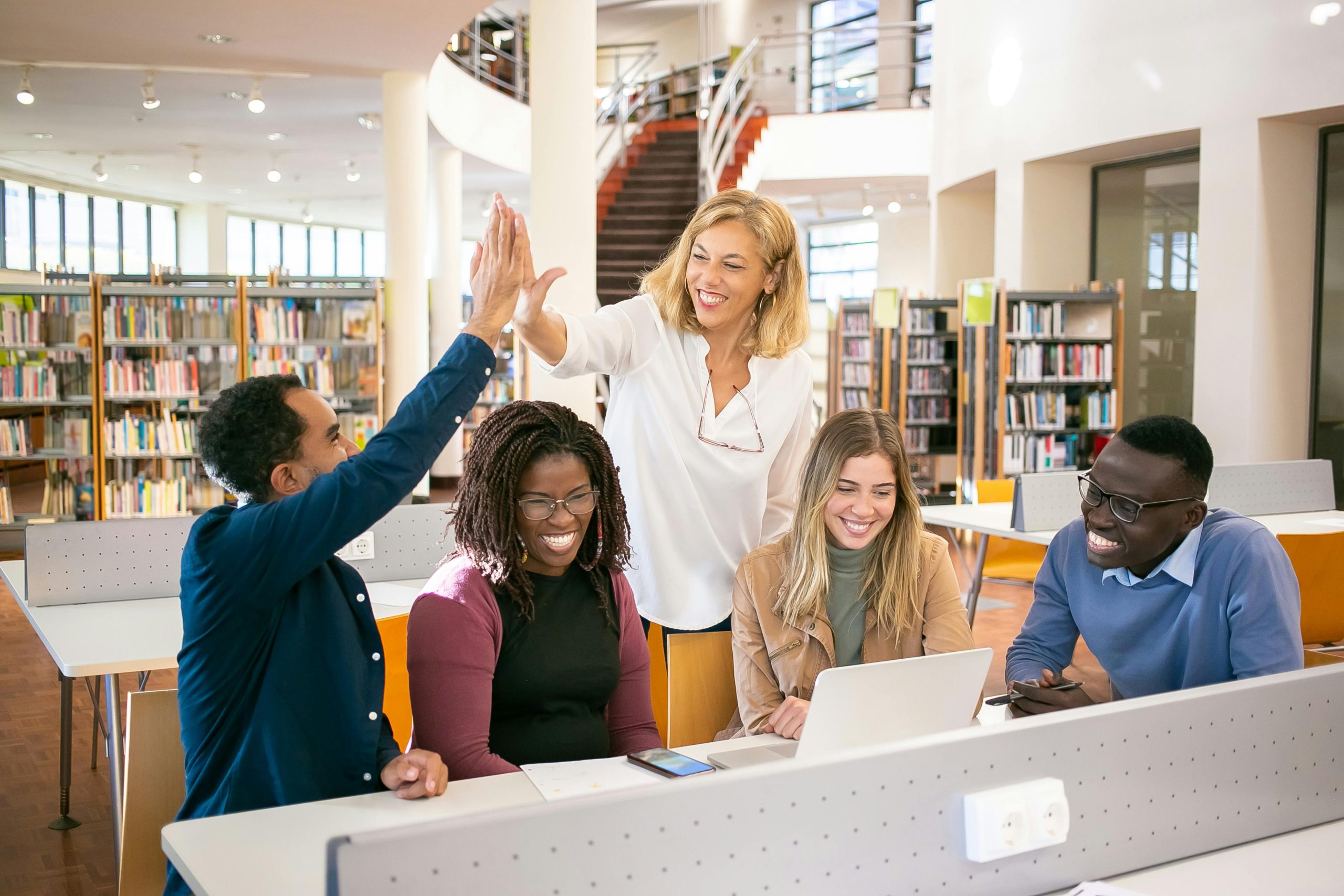 Teacher and tutor high fiving in library setting
