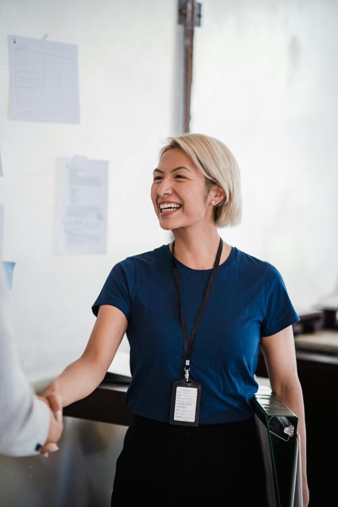 Lady in corporate wear smiling and shaking hands with person not in the picture