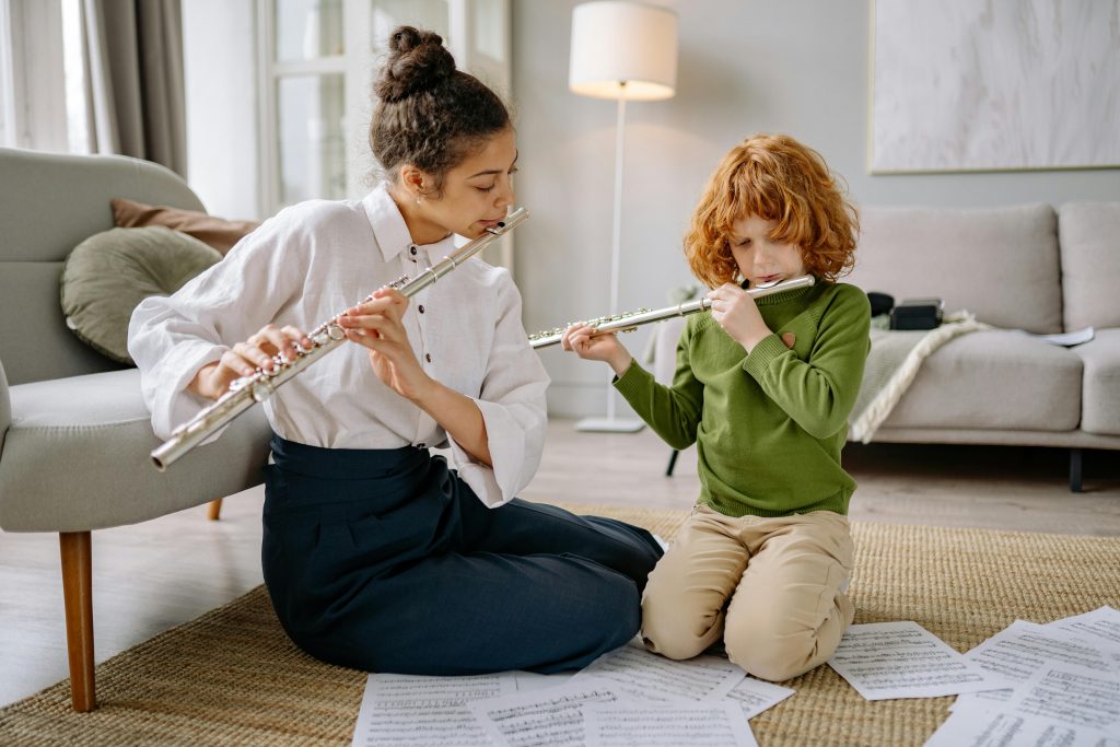 A lady and a red head young boy playing the flute